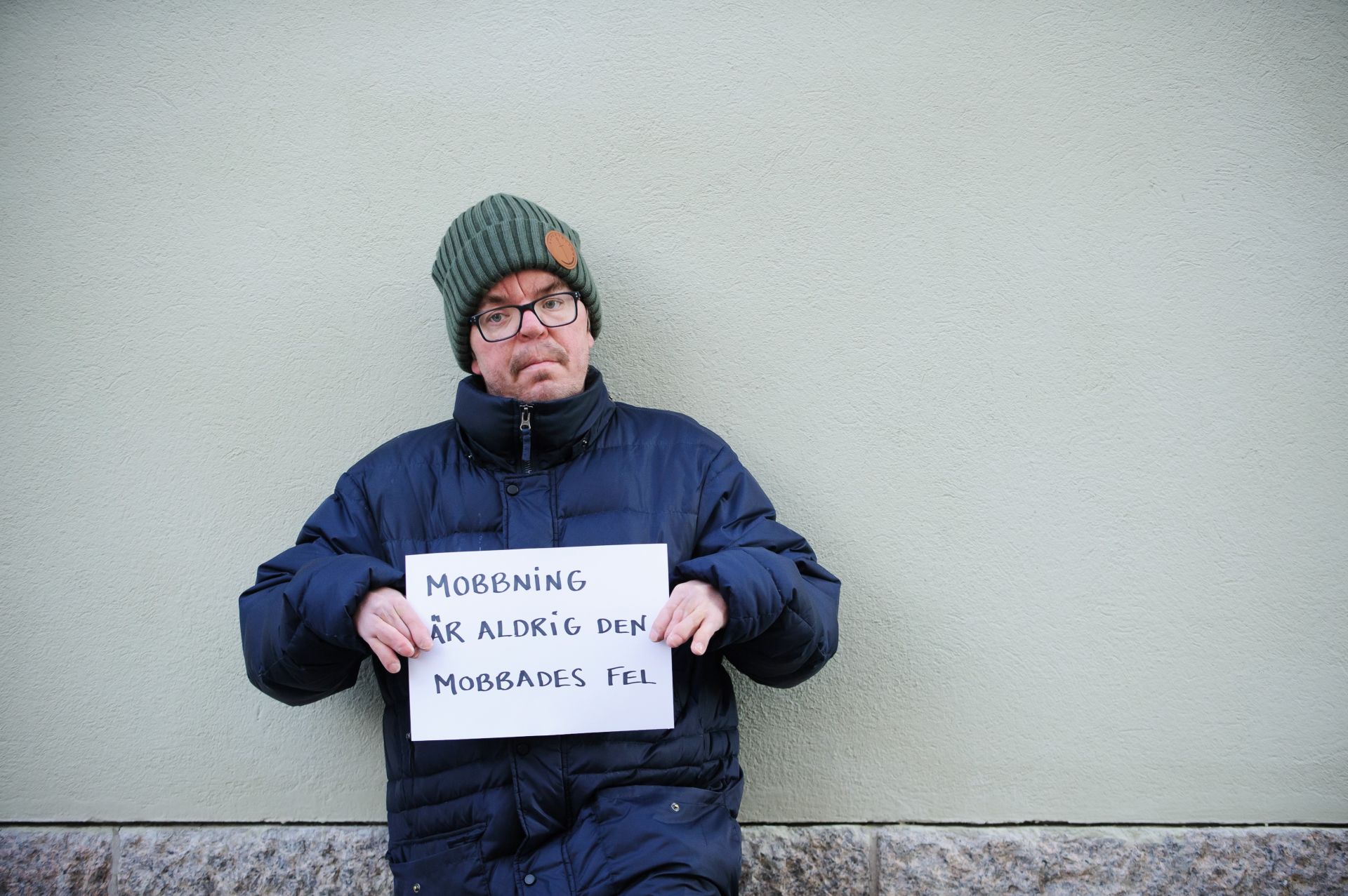 Jonne Tallberg med en skylt med texten Mobbning är aldrig den mobbades fel - vågrätt foto.