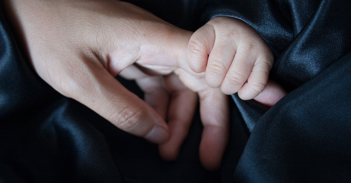 En babyhand som håller i ett vuxenfinger.
