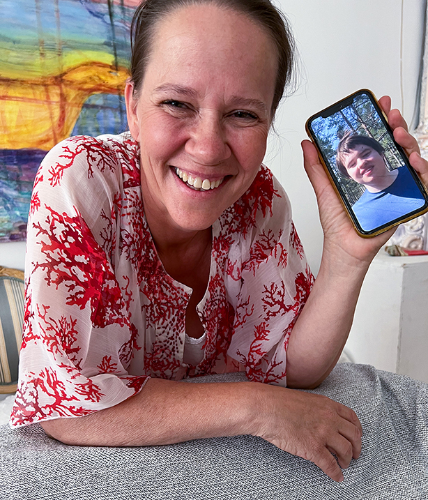 Leende kvinna visar upp foto på sin son på sin telefon.