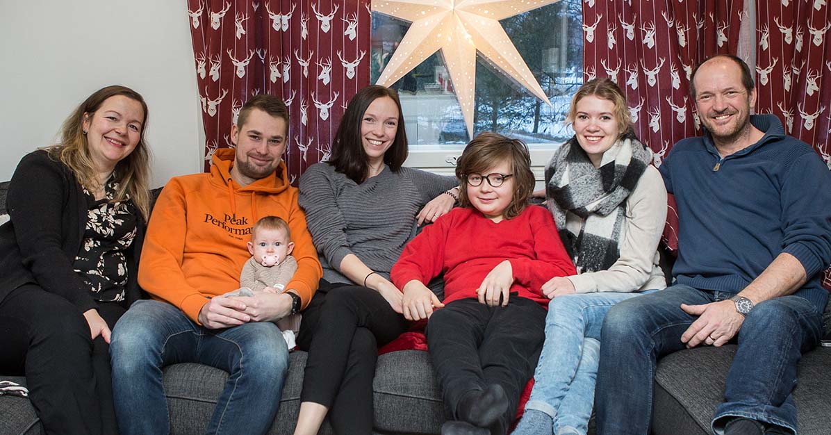 Ett familjeporträtt där alla sitter i soffan under en julstjärna.
