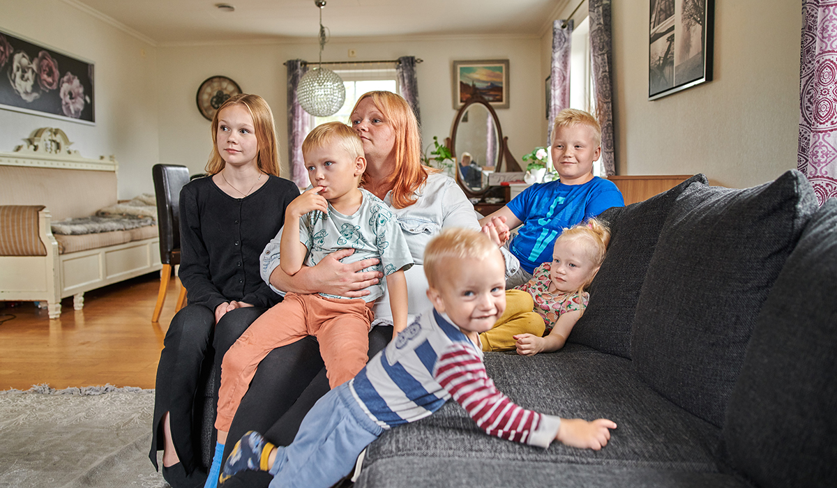 Fem barn i olika åldrar och en mamma i soffan.