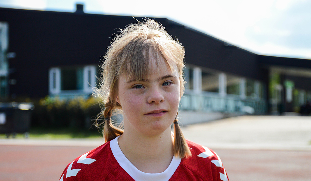 Ung flicka med Downs syndrom i fotbollströja.