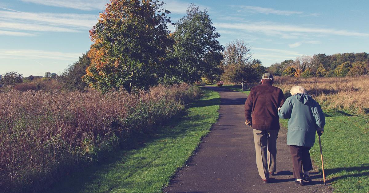 Ett äldre par går armkrok längs en väg