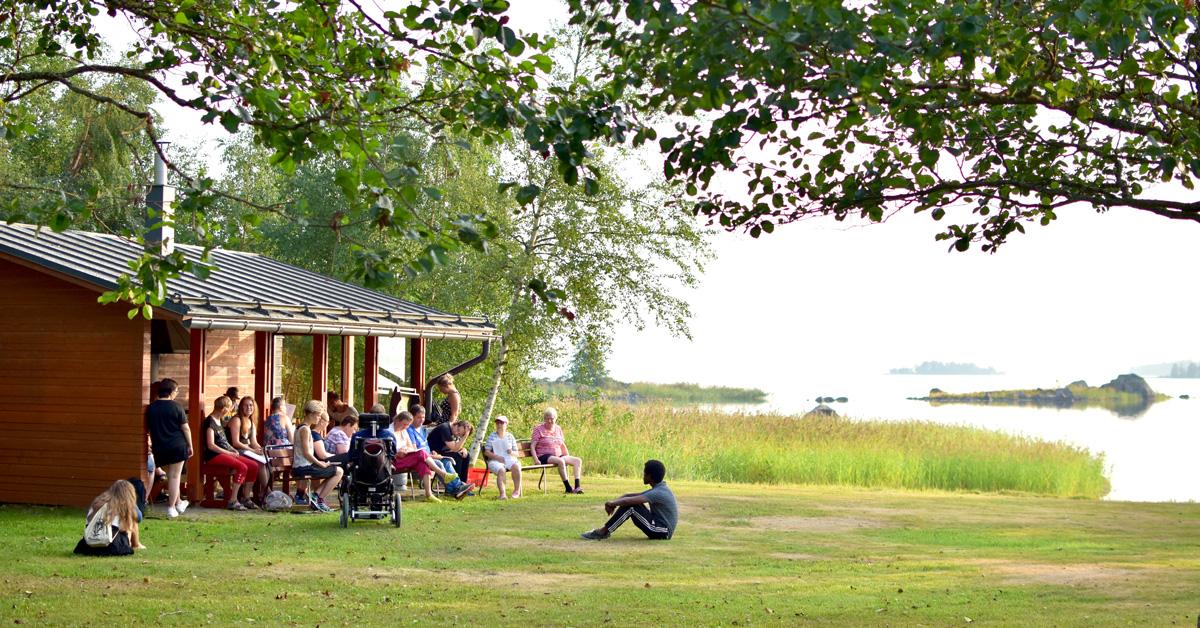 Flera personer vid en lägergård i somrig avslappnad miljö.