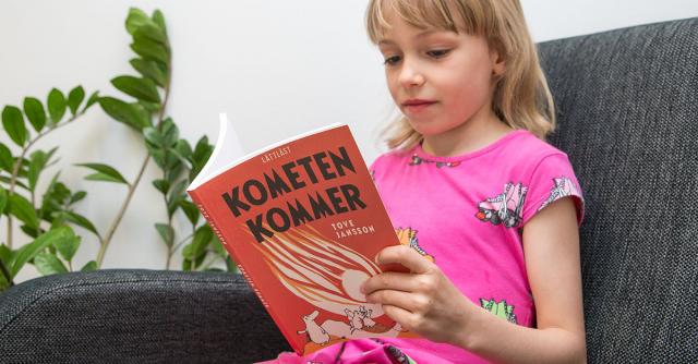 Flicka läser lättlästa mumikboken Kometen kommer.