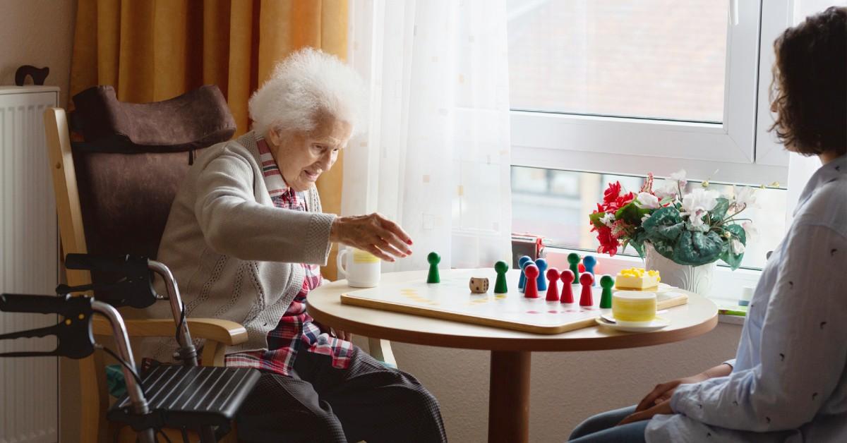 Ung kvinna spelar brädspel med äldre kvinna.