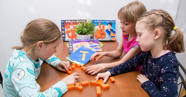 Flickor som leker med ett spel kring ett bord.