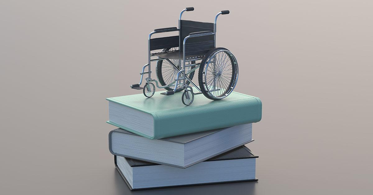 bild på en miniatyr rullstol på en hög av böcker.