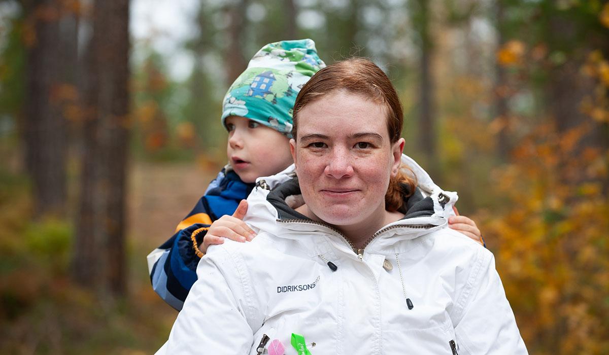 Andrea Westerlund i skogen med sonen Harald på ryggen.