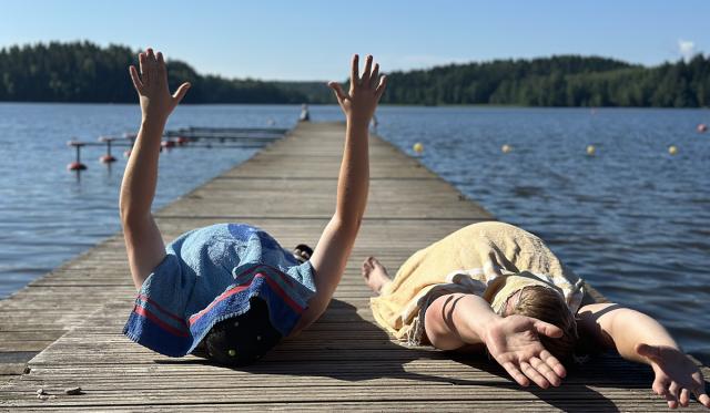 Två personer under handdukar på en brygga.