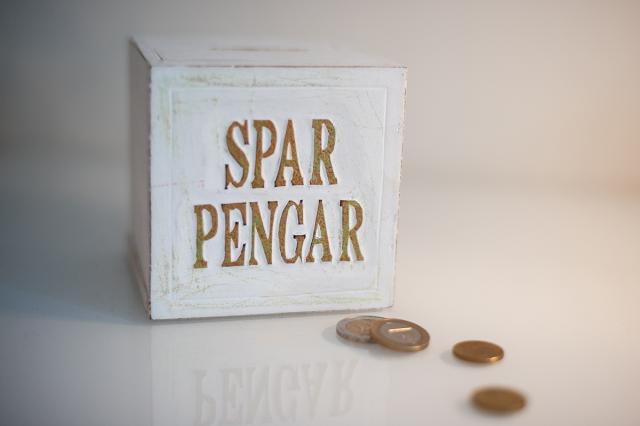 Några slantar vid en burk med texten sparpengar.
